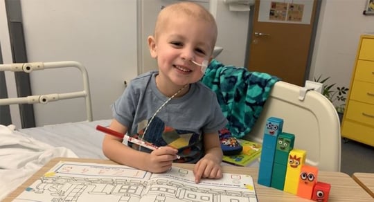 Smiling child colouring in his hospital room